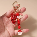 Detail van kerst sleutelhanger met kerstman hanger, rode bellen en een zuurstok bedel - Kerstman Kralen Bel Stijl