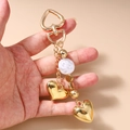 Dettaglio del portachiavi a cuore dorato con ciondoli lucidi ed eleganti perle sintetiche - Stile Disco Perla Cuore