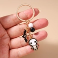 Close-up of Halloween keychain featuring bat pendant and skull charm with beads - Skeleton Bat Keychain