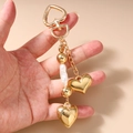 Dettaglio portachiavi a cuore dorato con perle e chiusura a molla per borsa di moda - Stile Cuore di Perle