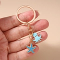 Detalle de llavero marino con pulpo azul claro y dije de estrella de mar dorada - Llavero de Estrella de Mar y Pulpo