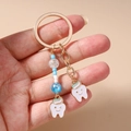 Detalle de llavero de diente lindo con cuentas de colores y aro dorado - Diente con Cuentas Azules