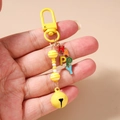 Detail view of colorful HAPPY letter charms and a yellow bell on a beaded keychain - Yellow Bell