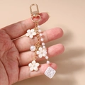 Dettaglio portachiavi con fiori bianchi, perle e ciondolo con carattere portafortuna - Fiore di Perla Bianca