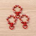 Close-up of three red floral spring ring keychains with polka dots on wooden surface - 5 Pieces / Red