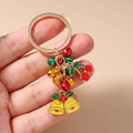 Dettaglio di un portachiavi natalizio con campanelli gialli, ciliegie rosse e anello oro - Portachiavi Campana Ciliegia