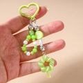 Dettaglio di portachiavi con perline verdi, chiusura a cuore e ciondolo a spirale - Lecca-lecca con Perline e Bottone Verde