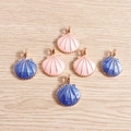Pink and dark blue enamel shell charms with golden alloy edges on a wooden background - Multicolor