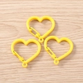 Vista ravvicinata di tre moschettoni in metallo giallo a forma di cuore su legno - Giallo