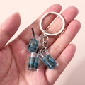 Detalle de llavero de té de burbujas azul con líquido brillante sobre fondo rosado - Azul