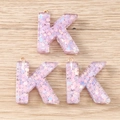 Détail de trois pendentifs lettre K en résine rose avec paillettes étoiles et anneaux dorés - Style Lettre K(K)