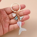 Detalle de llavero cola de sirena con escamas irisadas y dije de corazón en mano - Cola de Pez Azul