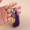 Detailansicht eines lila Quasten-Schlüsselanhängers mit Goldmünze und Traumfänger - Violette Quaste