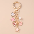 Detalle de un llavero dorado con concha estrella de mar y colgante de corazón - Estilo Estrella de Mar Corazón Rosa
