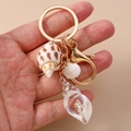 Detail of seashell keychain featuring a transparent conch pendant with real beach sand - White Conch