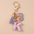 Detail of keychain showing purple tassel, butterfly charm, and sequined resin letter K - Butterfly Letter K