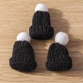 Close-up of three mini black knitted Christmas hats with white pom-poms on wood surface - 10 Pieces/Pack / Black