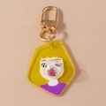 Makro-Detail des Comic-Mädchen-Schlüsselanhängers aus Acryl mit goldenem Metallverschluss - Gelb