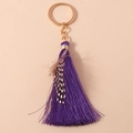 Close-up of purple tassel keychain with golden ring and spotted feather detail - Purple