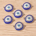 6er-Set Blaue Evil Eye-Anhänger mit weißen Strasssteinen auf hellem Holzgrund - Böses Auge