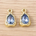 Tropfenförmige blaue Edelsteinanhänger mit Goldfassung auf hellem Holzgrund - Gold Blau