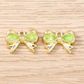 Ciondoli a fiocco dorati in lega con resina verde su sfondo in legno chiaro macro vista - Oro Verde
