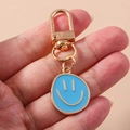 Porte-clés visage souriant en émail bleu ciel avec fermoir mousqueton doré - Bleu