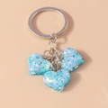 Détail macro de trois breloques cœurs bleu clair avec paillettes irisées sur porte-clés - Cœur à Paillettes Bleu
