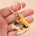 Close-up of golden graduation keychain with black mortarboard and yellow suede tassel - Round Ring - Doctoral Hat Yellow Tassel