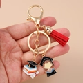 Detail of graduation girl keychain with red tassel and golden doctoral cap held in hand - Lobster Buckle - Doctoral Hat Red Tassel