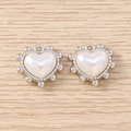 Vista dettagliata dei ciondoli a cuore in argento con centro perlato su fondo legno - Cuore di Perle Rotonde / 5 Pezzi / Argento