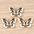 Makro-Detail von drei Emaille-Schmetterlingsanhängern mit Vergoldung für DIY-Schmuck - Schwarz-Weißer Schmetterling