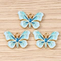 Detaillierte Makroansicht von drei blauen Emaille-Schmetterlingsanhängern mit Goldrahmen für DIY - Blauer Schmetterling