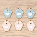 Detalle de dijes de huella con corazón en esmalte rosa y azul para joyería artesanal - Multicolor