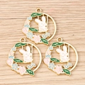 Macro detail of three enamel bunny wreath pendants on a light wood background - 10 Pieces Pack / Blue And Pink Flower Rabbit Ring