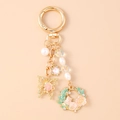 Detalle de llavero de gato rosa con mariposa, perlas y dijes de estrellas en metal dorado - Flor Rosa Perla Mariposa Gato