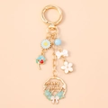 Detalle de llavero de esmalte dorado con dijes florales y corona de Happy Holidays - Corazón Azul Rosa Guirnalda Inglesa