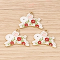 Detailed macro view of three enamel bunny pendants with red flower and gold metal edges - 10 Pieces Pack / Floral Rabbit