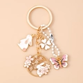 Dettaglio del portachiavi con coniglio dorato e ciondoli a forma di fiori e farfalla - Rosa Farfalla Coniglio Fiore