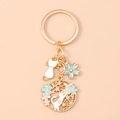 Detailed close-up of golden cat and cherry blossom keychain with blue floral charms - Blue Cat Flower