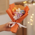 Detailansicht eines handgefertigten Häkel-Blumenstraußes mit bunten Garnblumen und orange Papier - Orange