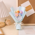 Nahaufnahme des handgehäkelten Blumenstraußes in blauem Papier mit Flower Party Schleife - Blau