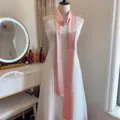 Dettaglio di un lungo foulard di raso rosa su un manichino davanti a una specchiera - Rosa