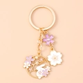 Detailed macro view of enamel rabbit and cherry blossom keychain with gold-plated finish - Flower Cat Wreath