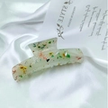 Large acetate hair claw clip with colorful glitter flakes on a white satin background - Translucent Green