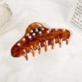 Large amber acetate hair claw clip with pearl embellishments on a white cloth background - Floral Orange