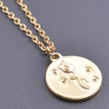 Détail macro du pendentif pièce dorée avec relief de tulipe et collier à chaîne croisée - Collier / Or