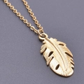 Vue macro d'un pendentif feuille dorée avec veines détaillées et fine chaîne dorée - Collier / Or