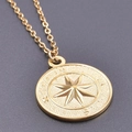 Dettaglio macro del ciondolo a bussola dorato con punti cardinali e design a stella - Set Ciondolo e Collana / Oro