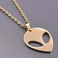Macro shot of 18K gold-plated alien head pendant with cutout eyes on a delicate link chain - Gold Necklace